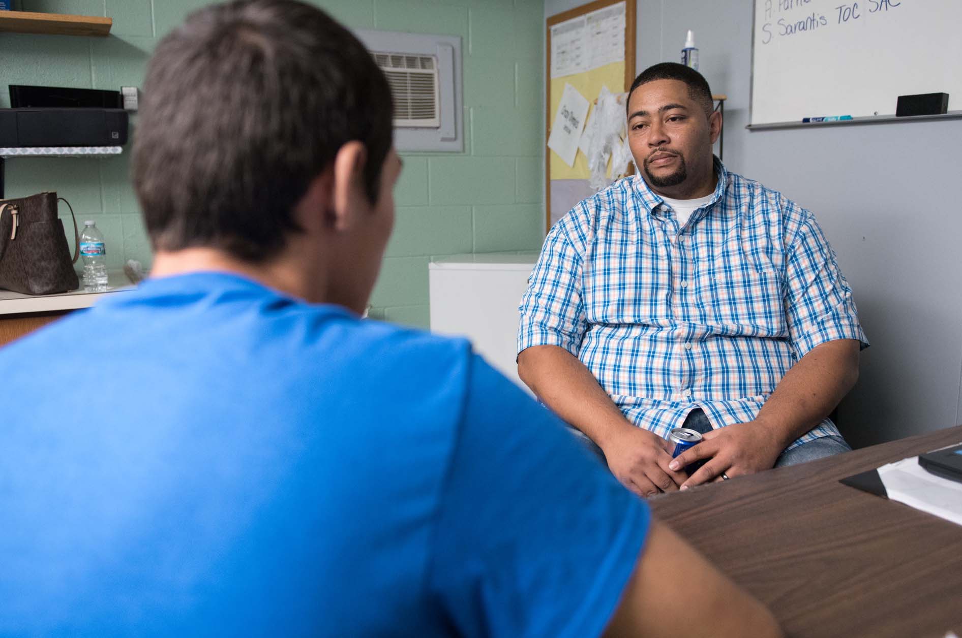 man facing camera talking with younger man with back to camera